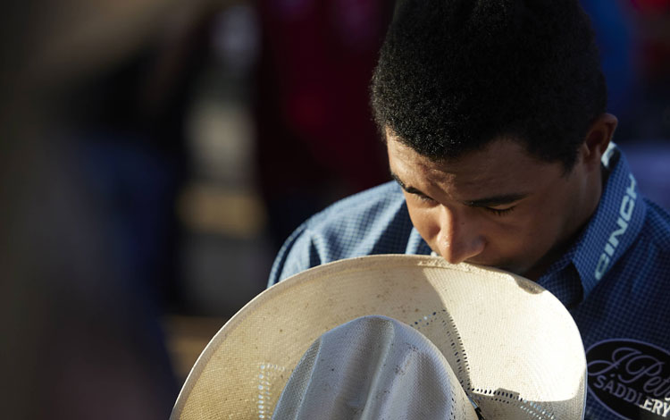 Laramie Mosley praying before the rodeo with his hat off.